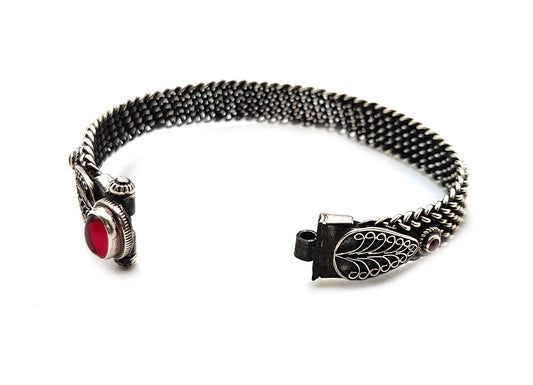 Close-up image of a 925 silver bangle adorned with rubies, showcasing its intricate wire design